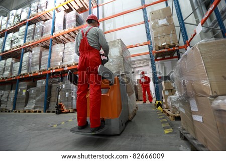 Goods delivery - two workers working in storehouse with forklift loader