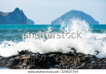 White wave splashes on the rocks with islands in the back near El Nido on Palawan island in Philippines