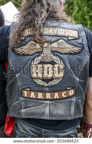 BARCELONA - JULY 06, 2014: Unidentified person with typical biker jacket a Harley Davidson motorbike at an exhibition during BARCELONA HARLEY DAYS 2014. Distinctive groups and related associations.