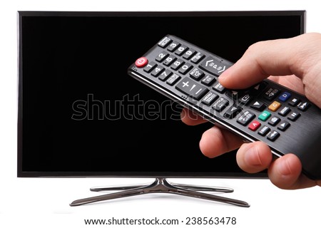 Hand holding TV remote control with a smart tv in the background