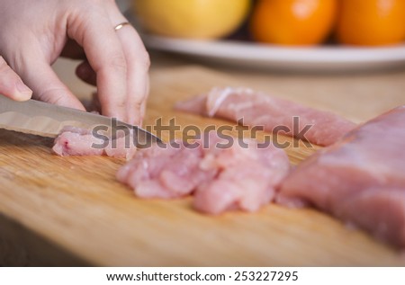 Man\'s hand cutting chicken breast