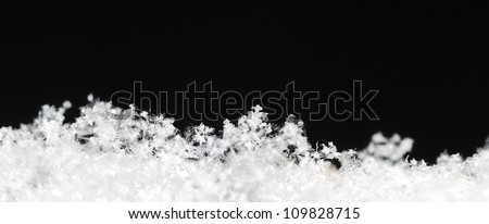 Small white background with black snow crystals in the black winter panorama