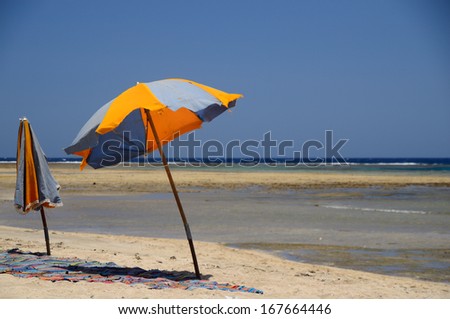 two colorful umbrellas are at the sand beach by the sea on vacation