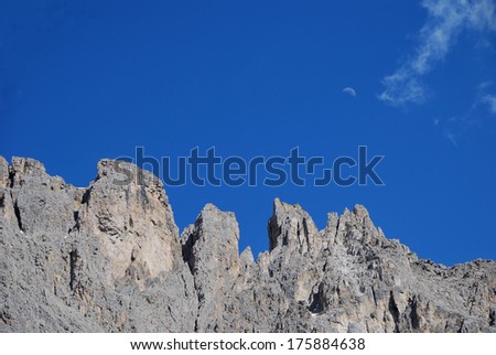 high gray rocky mountains with blue sky and moon