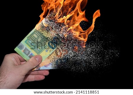 three burning euro bank notes held in one hand decomposes and dissolves due to inflation with black background Foto stock © 