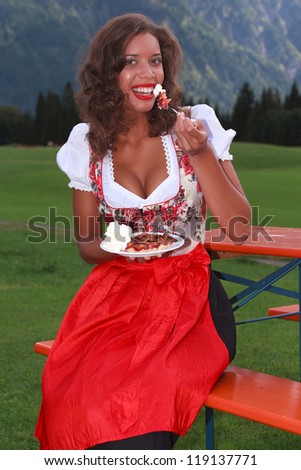 Young girl in traditional Bavarian costume eating a cake
