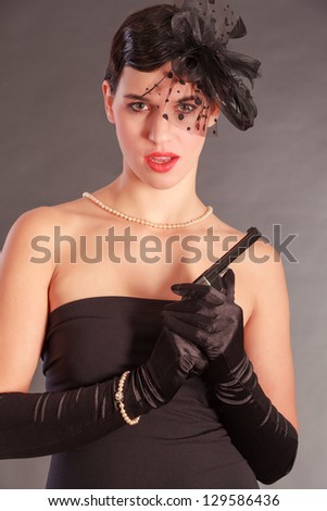 Elegant woman in black dress with gun and bow in her hair /Wonderful woman in Agent Look