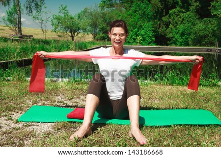 Mature woman making gymnastics outdoors /Iyengar yoga: health, body and soul