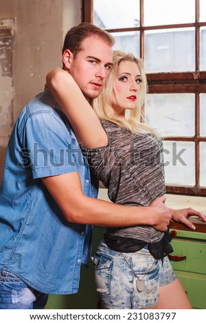 Attractive young couple hugging each other in a relationship, standing sideways to the camera. / Attractive young couple in a relationship