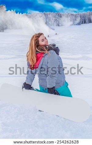 Young woman with a snowboard on the ski slopes, kneeling in the snow, with his back to the camera, looking over her shoulder./Young chubby woman with a snowboard on the ski slopes,kneeling in the snow