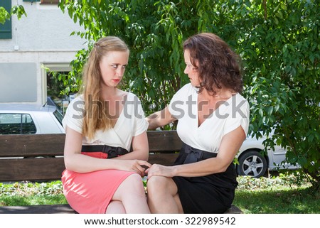 Two Women Dressed in Formal Clothing Having Serious Heartfelt Conversation Together While Sitting on Park Bench on Sunny Summer Day