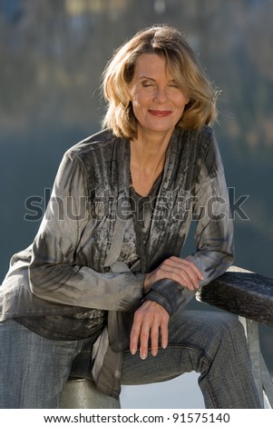 Older lady enjoys the morning sun on the lake / woman dreaming