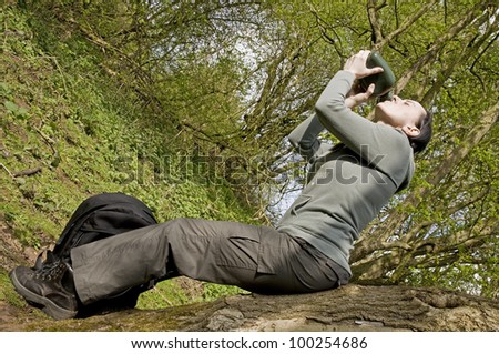 woman drinking from water bottle in woodland