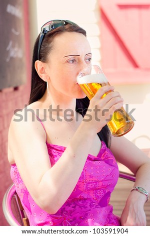 woman drinking a pint of lager in a pub beer garden portrait