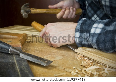 a carpenter at work using using a chisel and hammer on wood