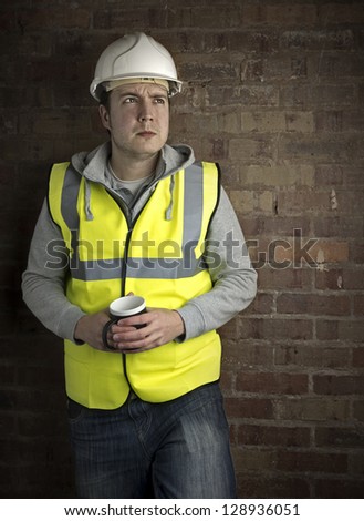 construction worker / builder on coffee break leaning against brick wall looking up
