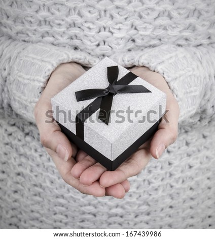 woman holding silver gift box with black ribbon
