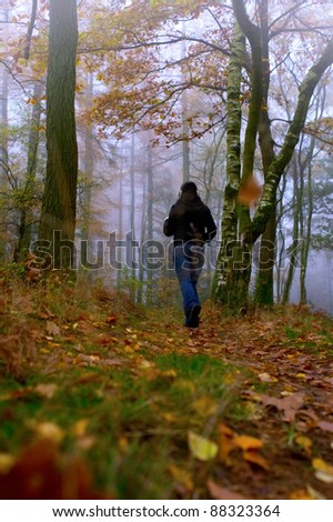 early morning jog in autumnal woodland with fog