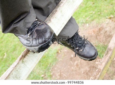 person climbing over fence wearing walking boots