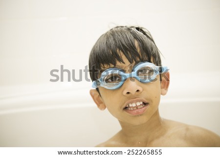 A wet kid with goggles is looking at the camera