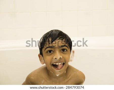 A little boy smiling at the camera with soap lather (foam) all over the face.