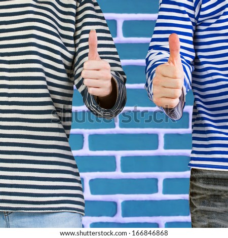 Man and woman with thumbs up sign over brick wall with copy space. Young couple showing thumbs up sign