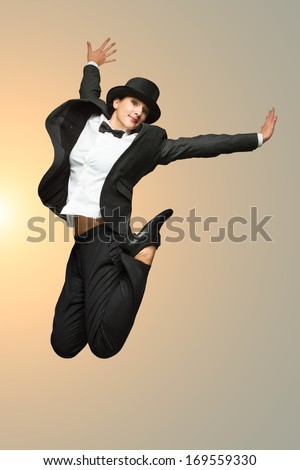 Happy young woman wearing vintage costume jumping against light background with copy-space. Woman wearing retro suit and top hat jumping