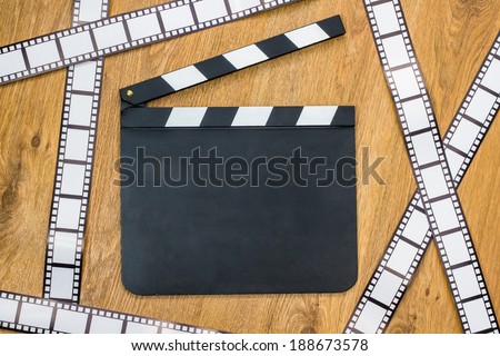 Blank film slate and film stripes on a wooden background