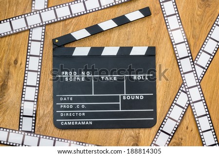 Film slate and film stripes on a wooden background