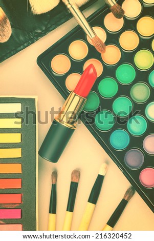Overhead view of makeup cosmetics collection - lipstick, palette, professional makeup brushes etc. Toned image