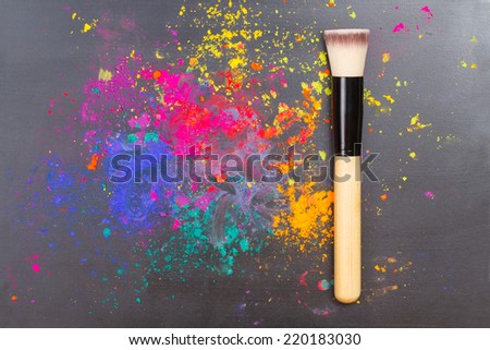 Makeup brush on a background with colorful powder. Makeup concept
