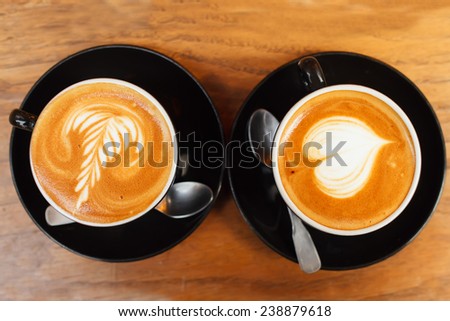 Coffee foam decoration arts. Two cups of coffee on a wooden table, shallow DOF