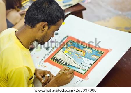 UDAIPUR, INDIA - 10 DEC, 2011: Young Indian man in yellow t-shirt painting the picture of Udaipur city with oil colors
