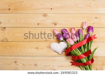 Tulip bouquet with red ribbon and fabric handmade heart on natural wooden texture