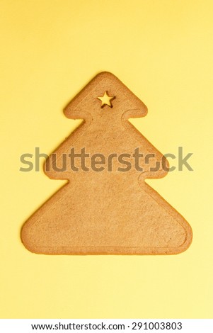 Sweet gingerbread cookie shaped like a Christmas tree on yellow. Sweet Xmas treat