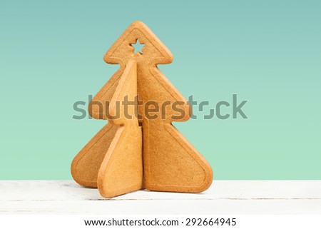 Decorated Christmas cookie shaped like a Christmas tree on blue background with copy space