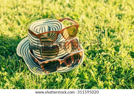 Hat with various sun glasses on green grass outdoors