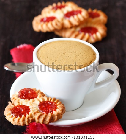 Cup of coffee and cookies with jam on a dark wooden background.