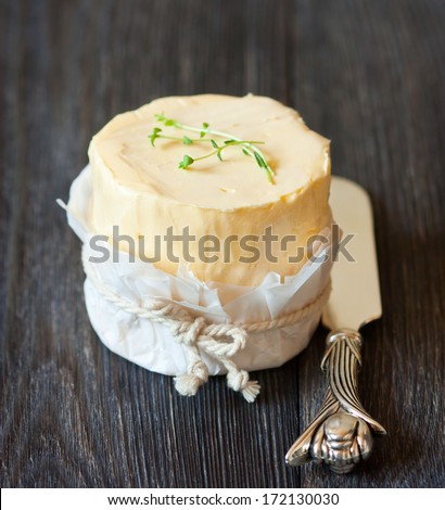 Fresh organic butter and knife on a wooden board.