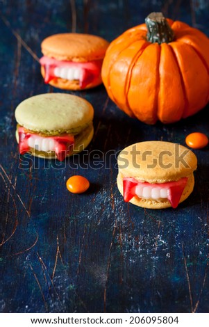 Halloween scary cookies with vampire teeth and pumpkin on dark blue board with copy space.