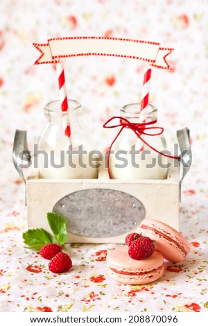 School milk bottles with decorative name tag and macarons with fresh berries.