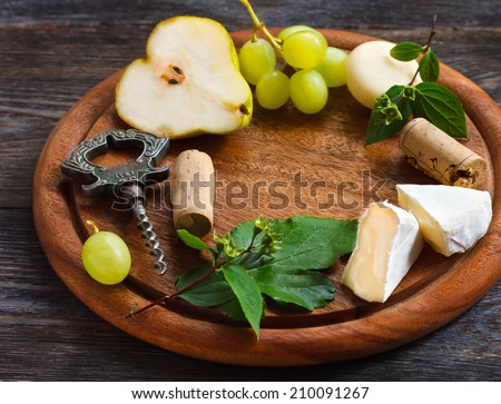 Wine frame background. Cheese and fruit on a wooden serving board.