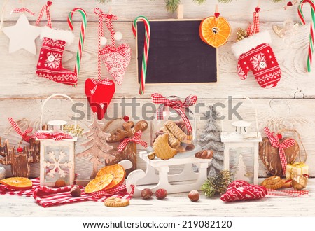 Christmas decorations with cookies in a glass bell jar on a sledge with place for greeting on chalk blackboard. Toned photo.