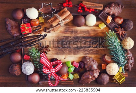 Christmas food background. Chocolate truffles, candied fruit, nuts and christmas spices on a wooden background with place for text. Toned photo.