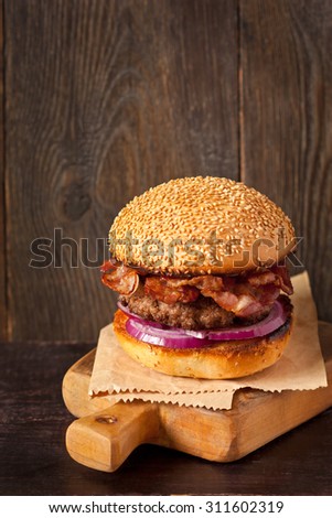 Brutal smoked bacon hamburger on wooden cutting board.