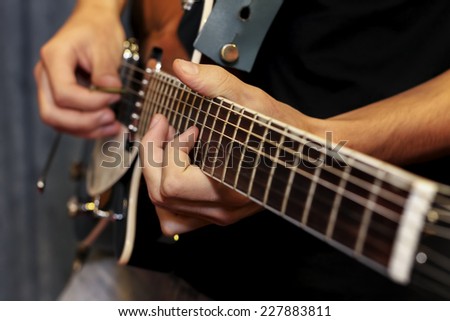 close up shot of a man with his fingers on the frets of a guitar playing