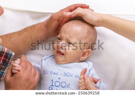 parents calm a crying baby stroking it on his head