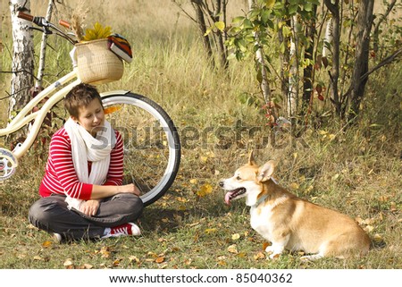 Beautiful girl and corgi dog relaxing near the bike