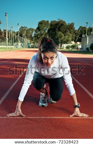 Female athlete/sprinter in \'on your marks, get set, go\' starting starting position.