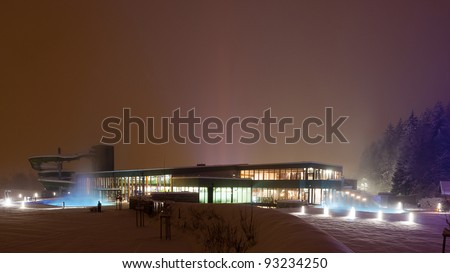 modern building by night and many lights with steaming oudoor swimming pools and tower of a water slide